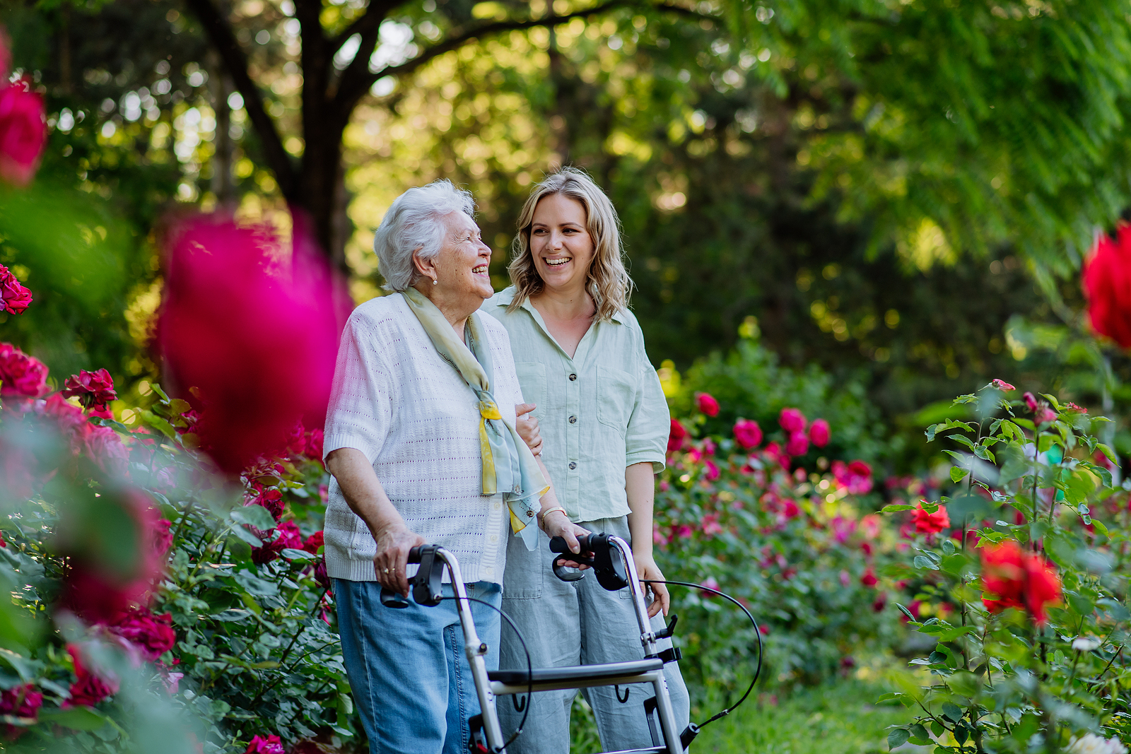 Senior and adult granddaughter walking in garden