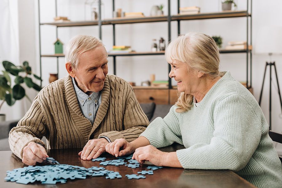happy senior couple playing with puzzles at home