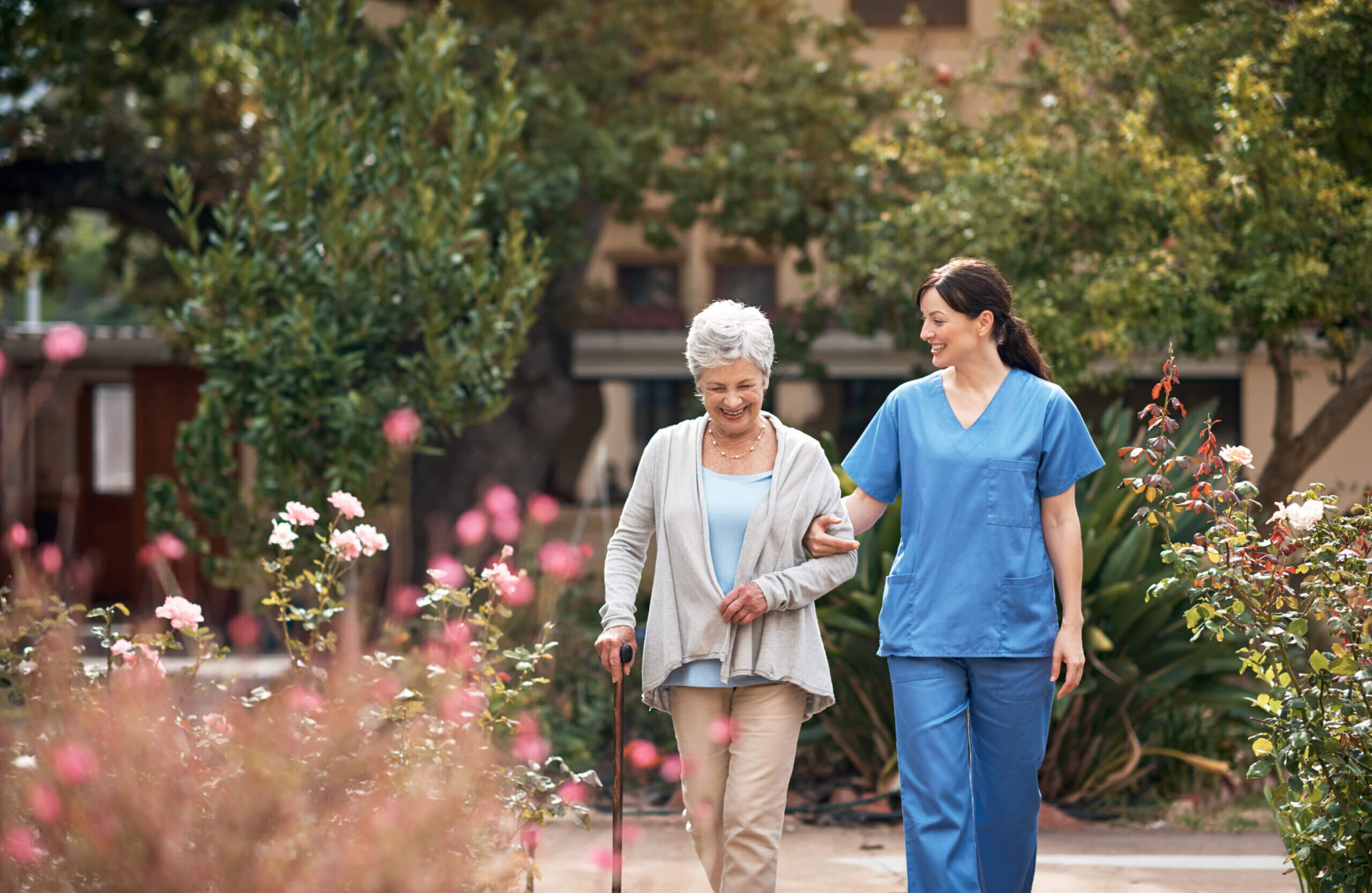 Caregiver helping woman through garden